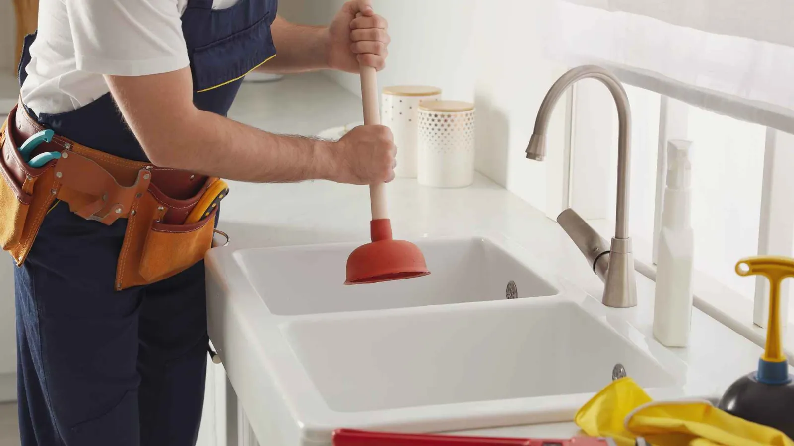 Monteur ontstopt een keukenspoelbak met een plopper